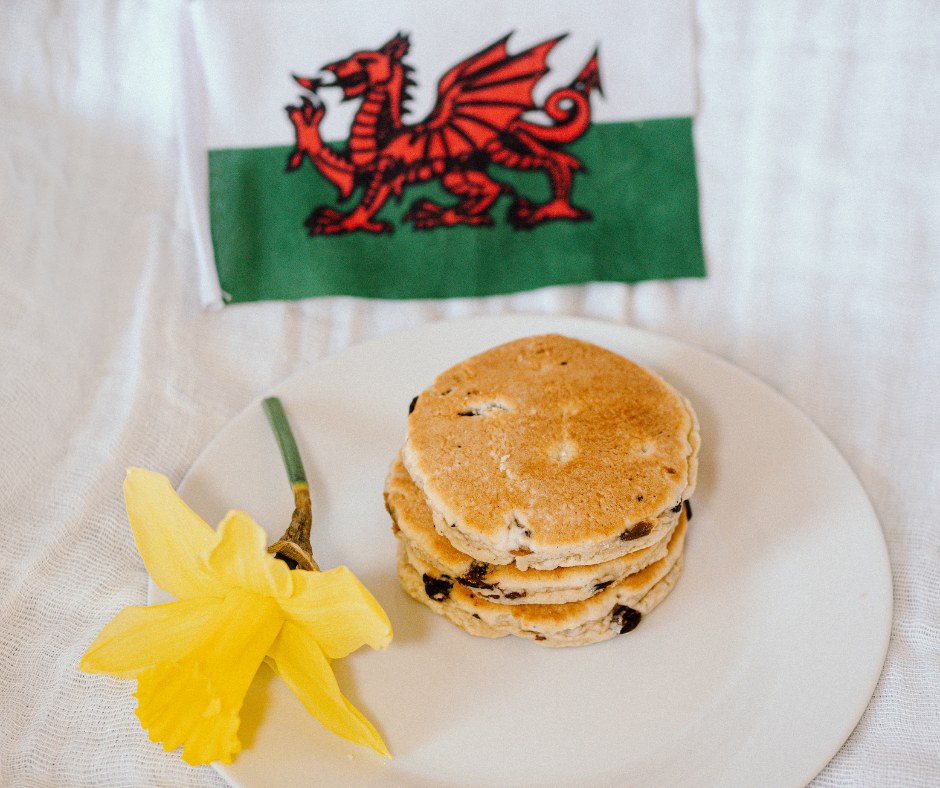 Welsh flag, pancakes, daffodil on table.