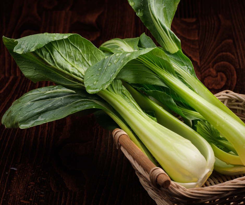 Fresh bok choy in basket on wooden table.