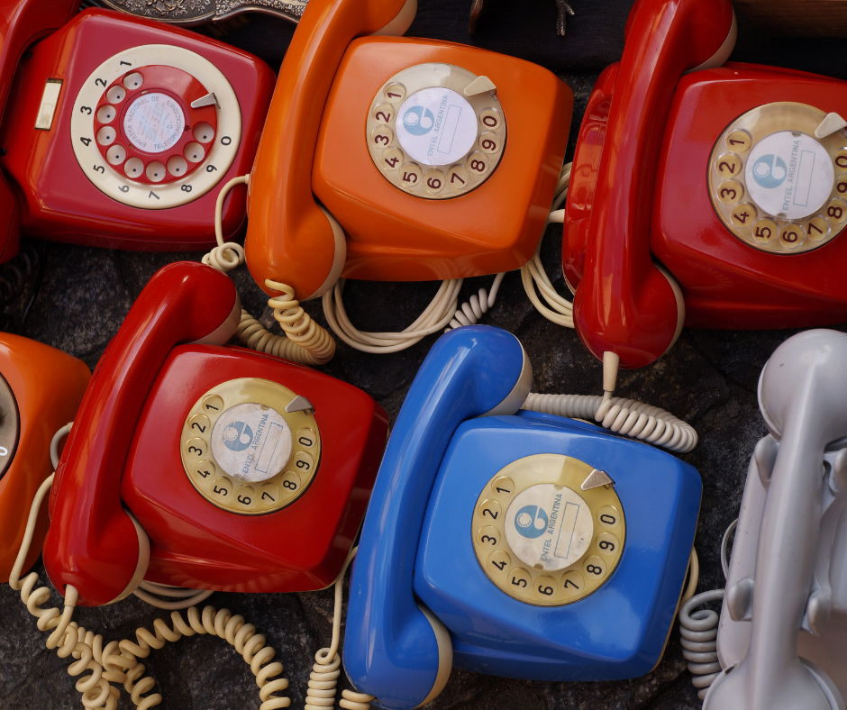 Vintage rotary dial telephones in various colours.