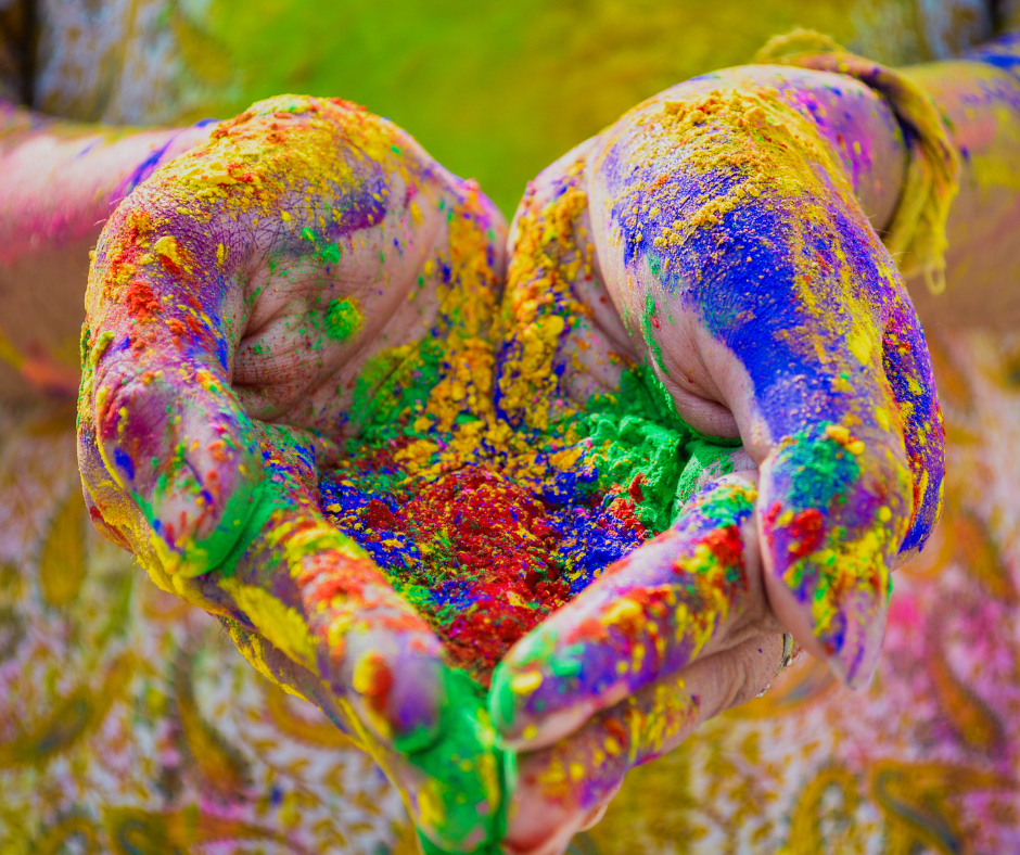 Colourful painted hands cupping vibrant powder.