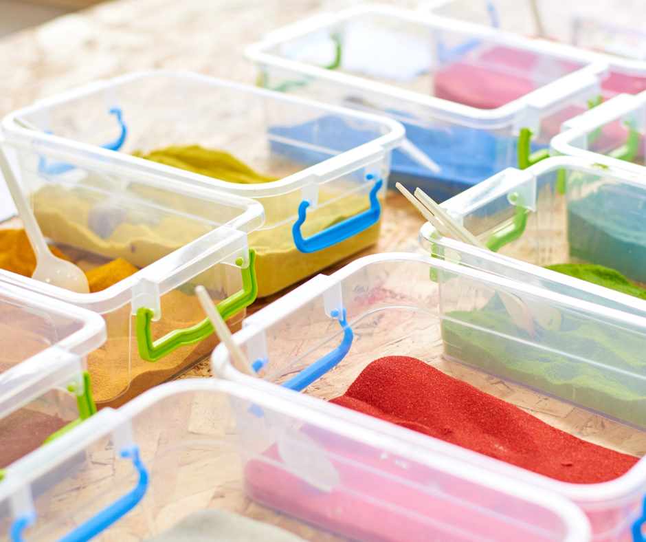 Colourful sand in clear plastic containers with scoops.