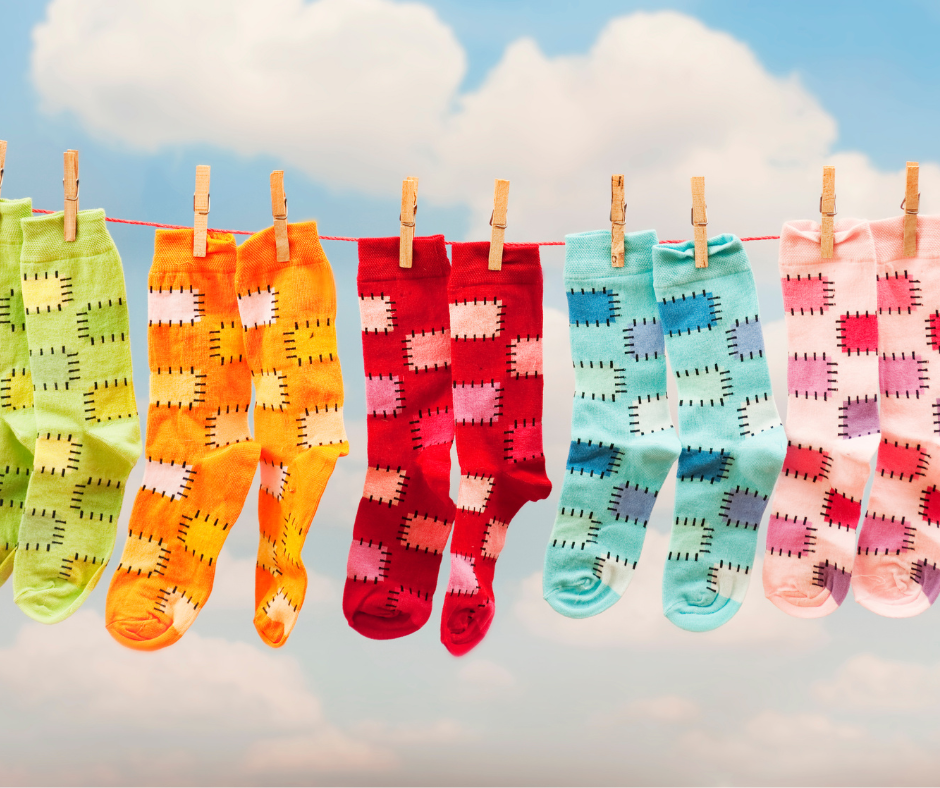 Colourful socks hanging on clothesline against sky.
