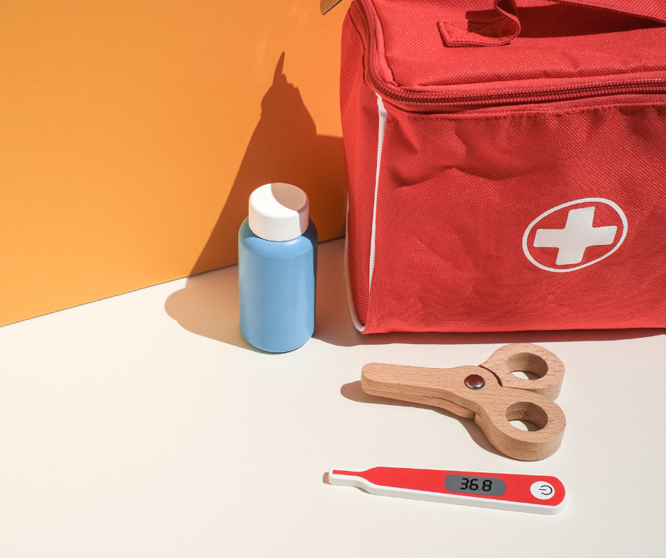 First aid kit, thermometer, and medicine bottle on table.