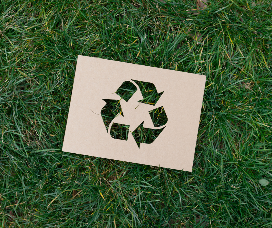 Recycling symbol cut-out on grass background.