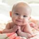 Smiling baby lying on colourful blanket