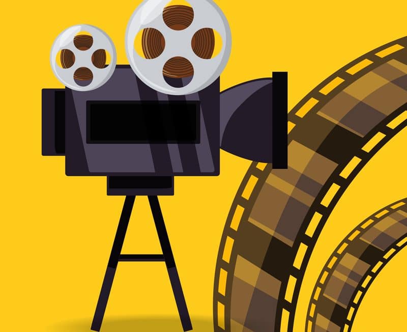 Retro film projector with reels on yellow background.