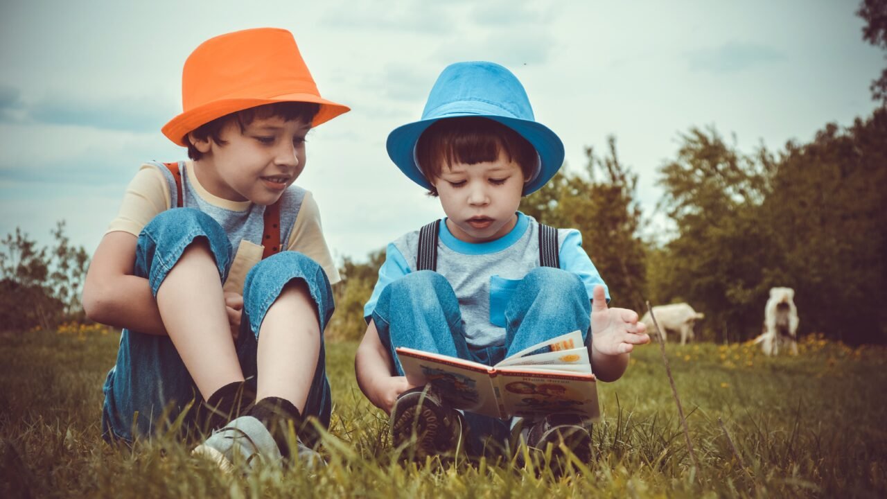 Two boys reading book in grassy field